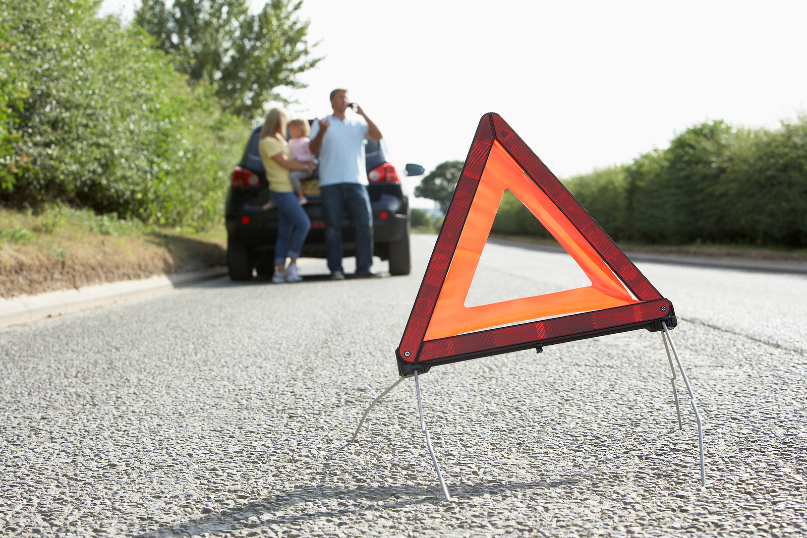 Family Broken Down On Country Road With Hazard Warning Sign In F